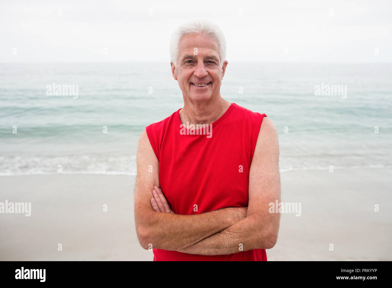 Portrait of senior man standing with arms crossed on beach Stock Photo