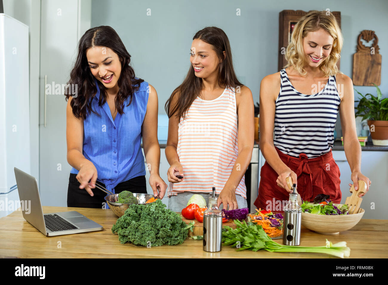 Happy female friends preparing food in kitchen Stock Photo