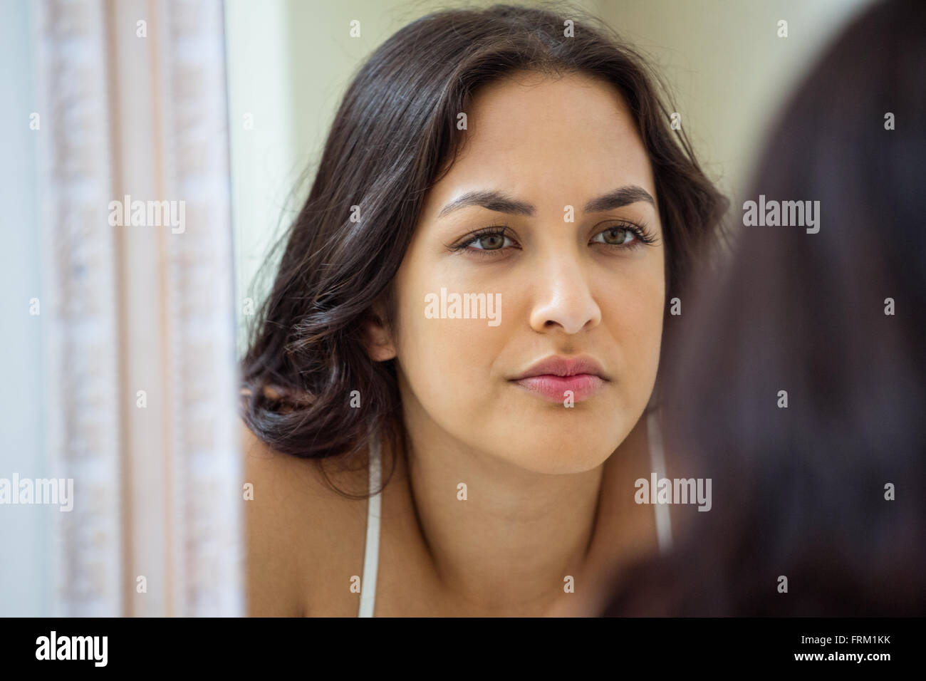 Young woman looking in mirror of bathroom Stock Photo - Alamy