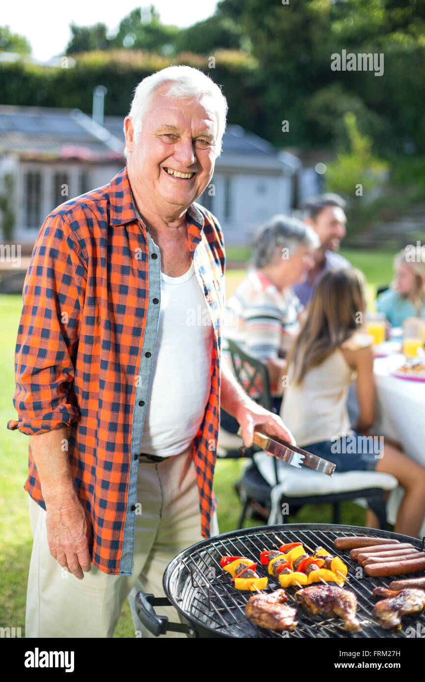 Portrait of senior man preparing food on barbecue Stock Photo