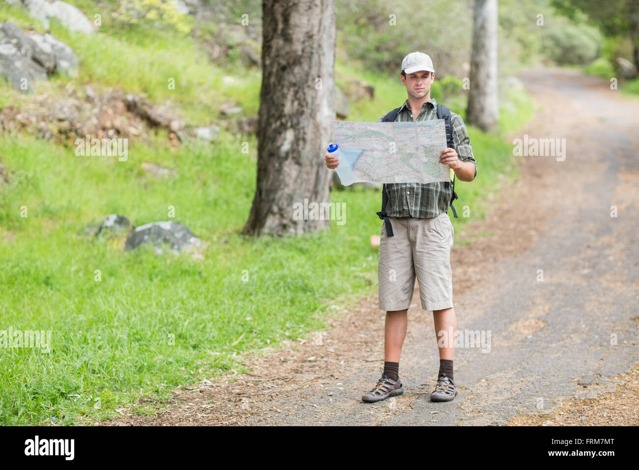 Handsome young man with backpack - Young Man Reading Map On Footpath In Forest FRM7MT
