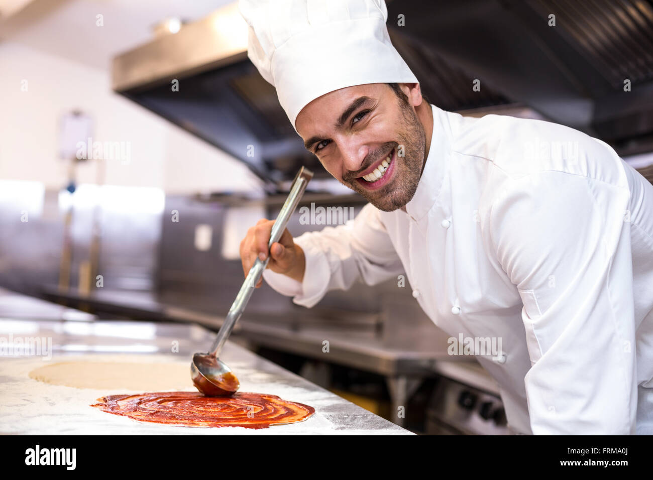 Pizza chef put sauce on base Stock Photo