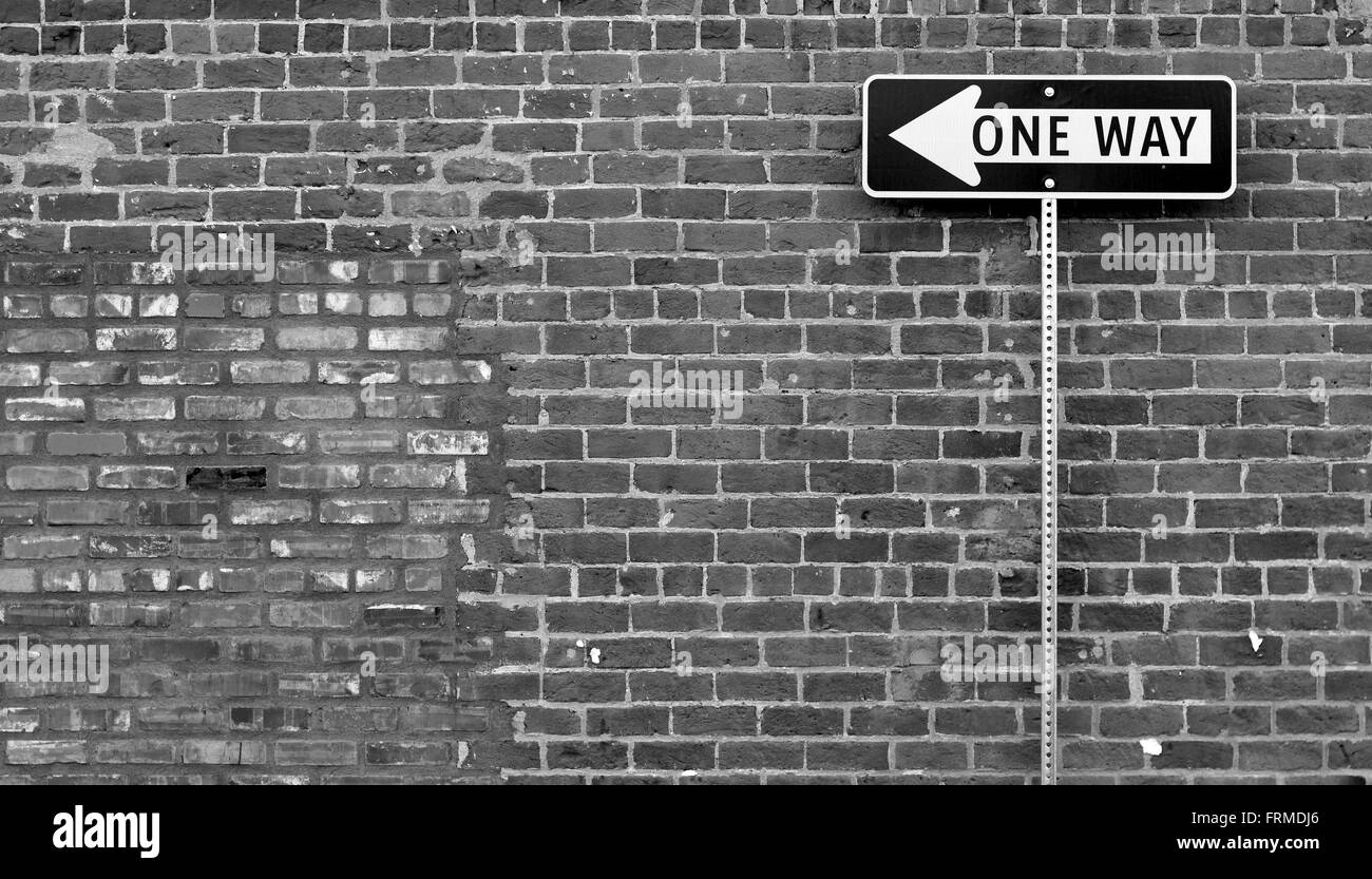 One Way street sign in black and white with brick building behind it ...