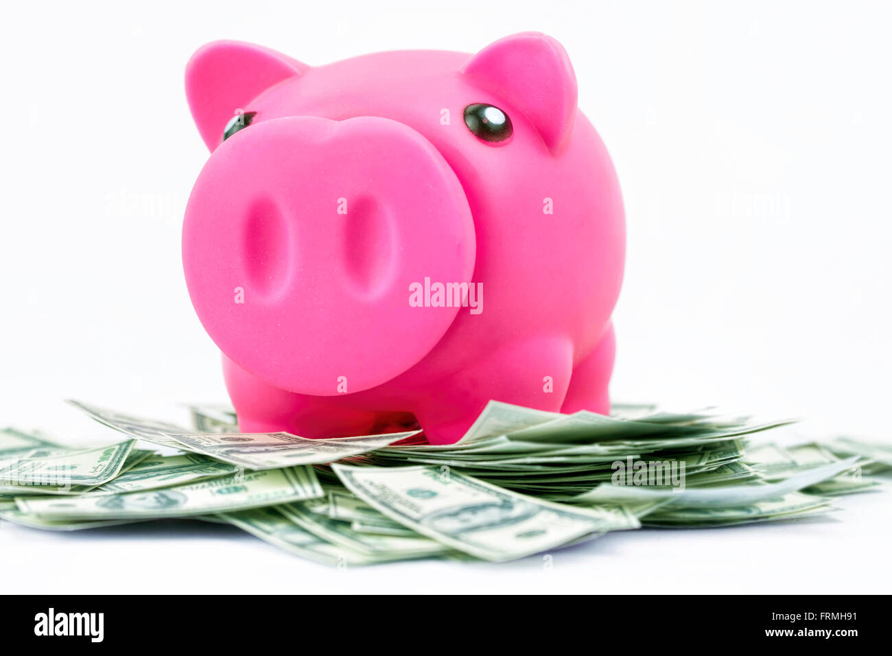 Piggy bank on pile of 100 dollar notes Stock Photo