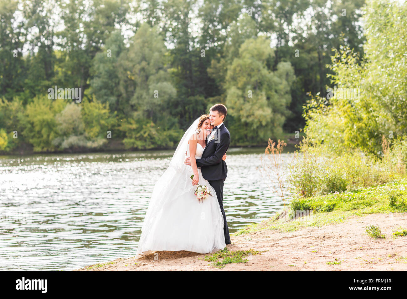 Wedding couple standing and hugging near lake Stock Photo - Alamy