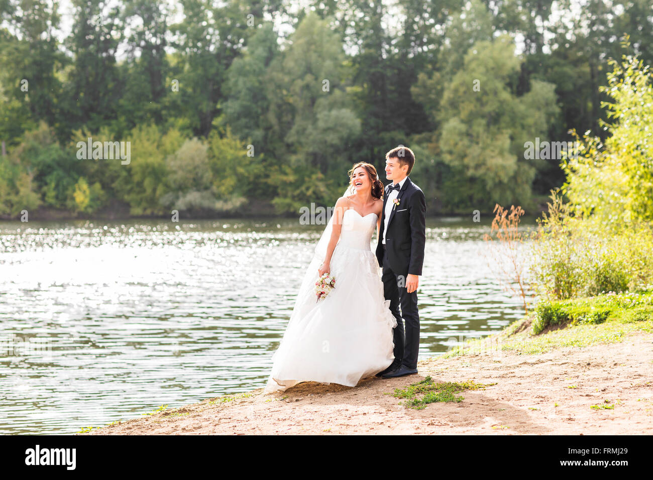 Wedding couple standing and hugging near lake Stock Photo - Alamy