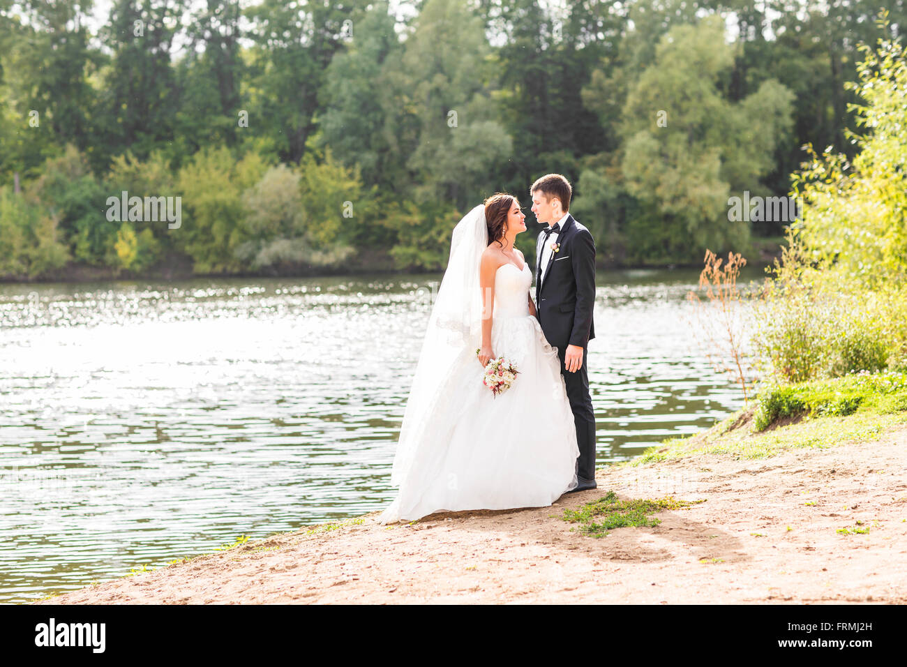 Wedding couple standing and hugging near lake Stock Photo - Alamy