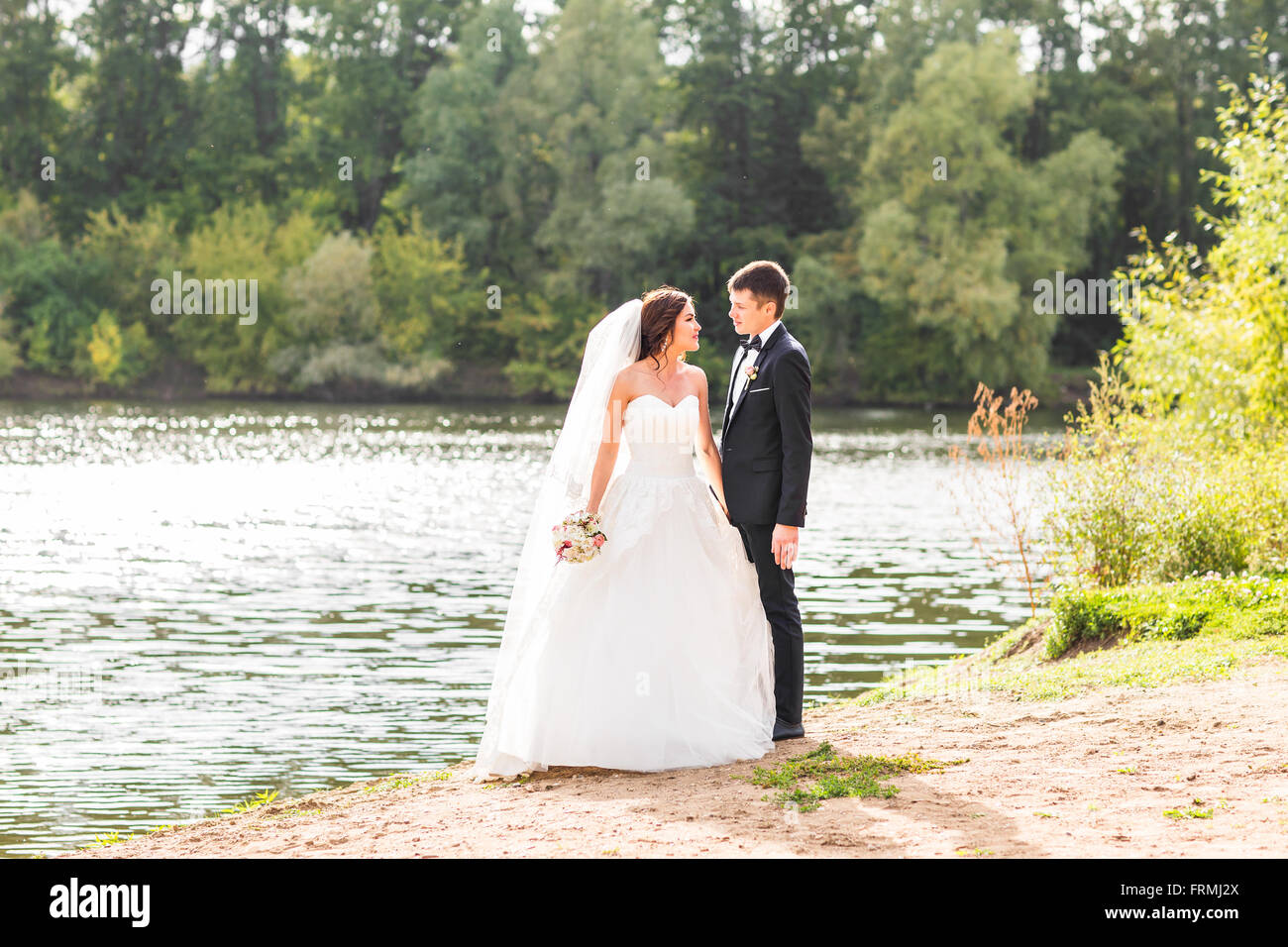 Wedding couple standing and hugging near lake Stock Photo - Alamy