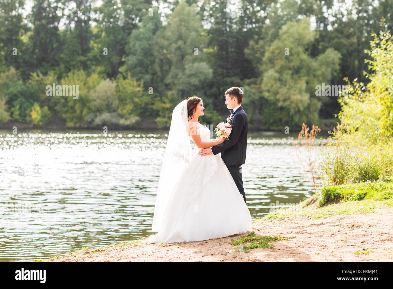 Wedding couple standing and hugging near lake Stock Photo - Alamy