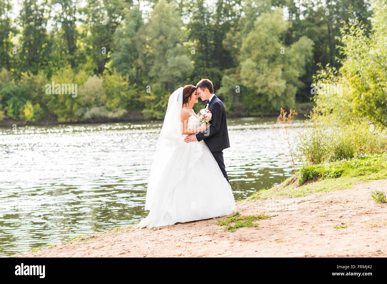 Wedding couple standing and hugging near lake Stock Photo - Alamy
