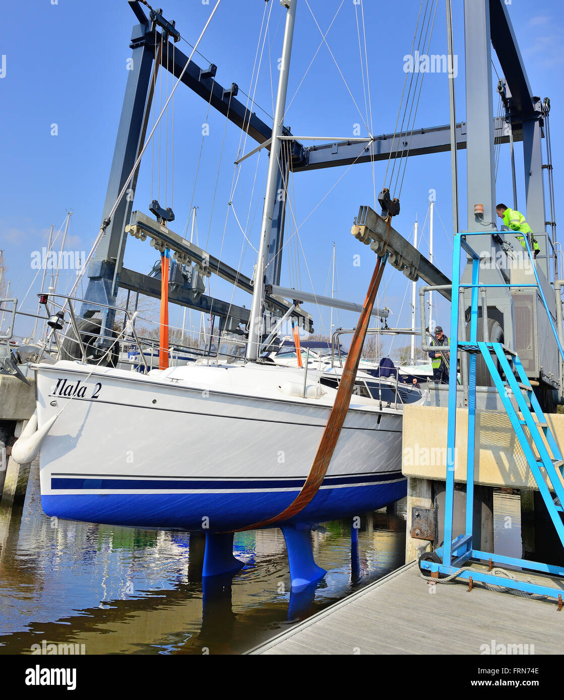 Yacht being hoisted into the water again after winter storage ashore  on the hard standing in Premier Chichester marina - Chichester, West Sussex, UK Stock Photo