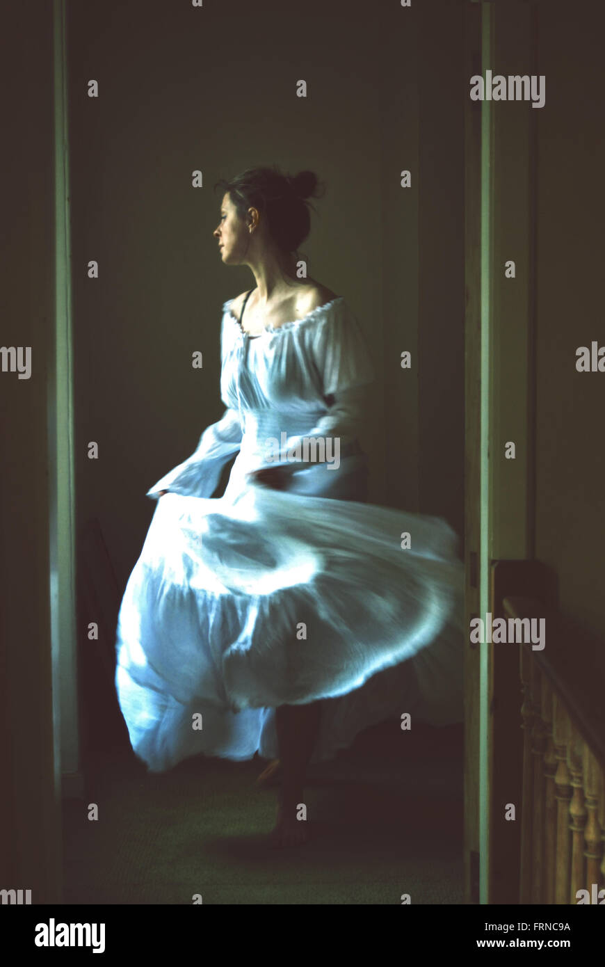young woman dancing in an old house wearing white long romantic dress Stock Photo