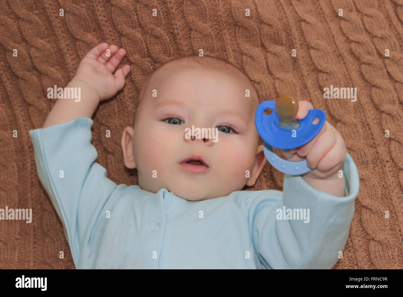 Baby boy holding a blue nipple Stock Photo
