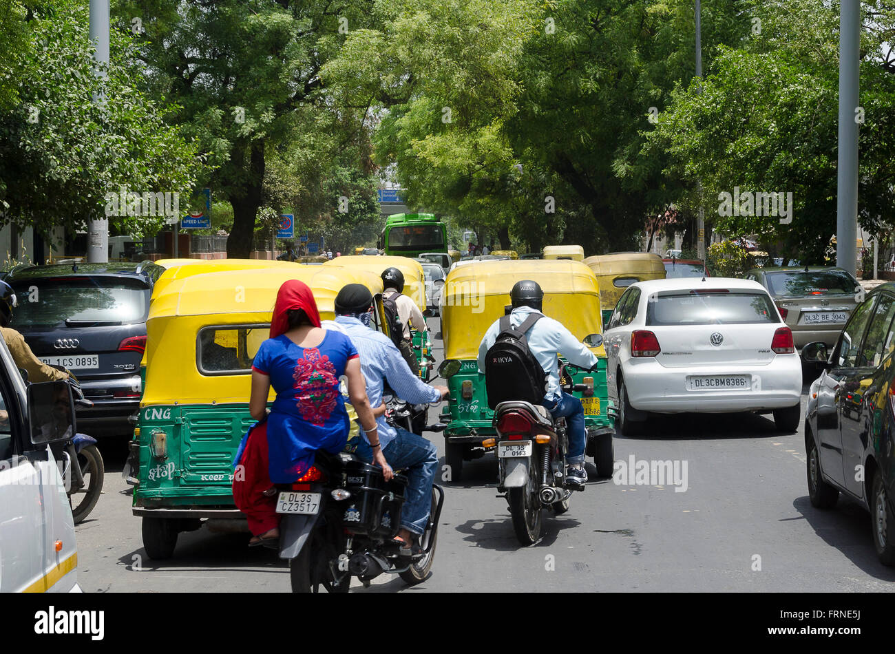 Couple on motorcycle in traffic with Tuk tuks, Delhi, India Stock Photo