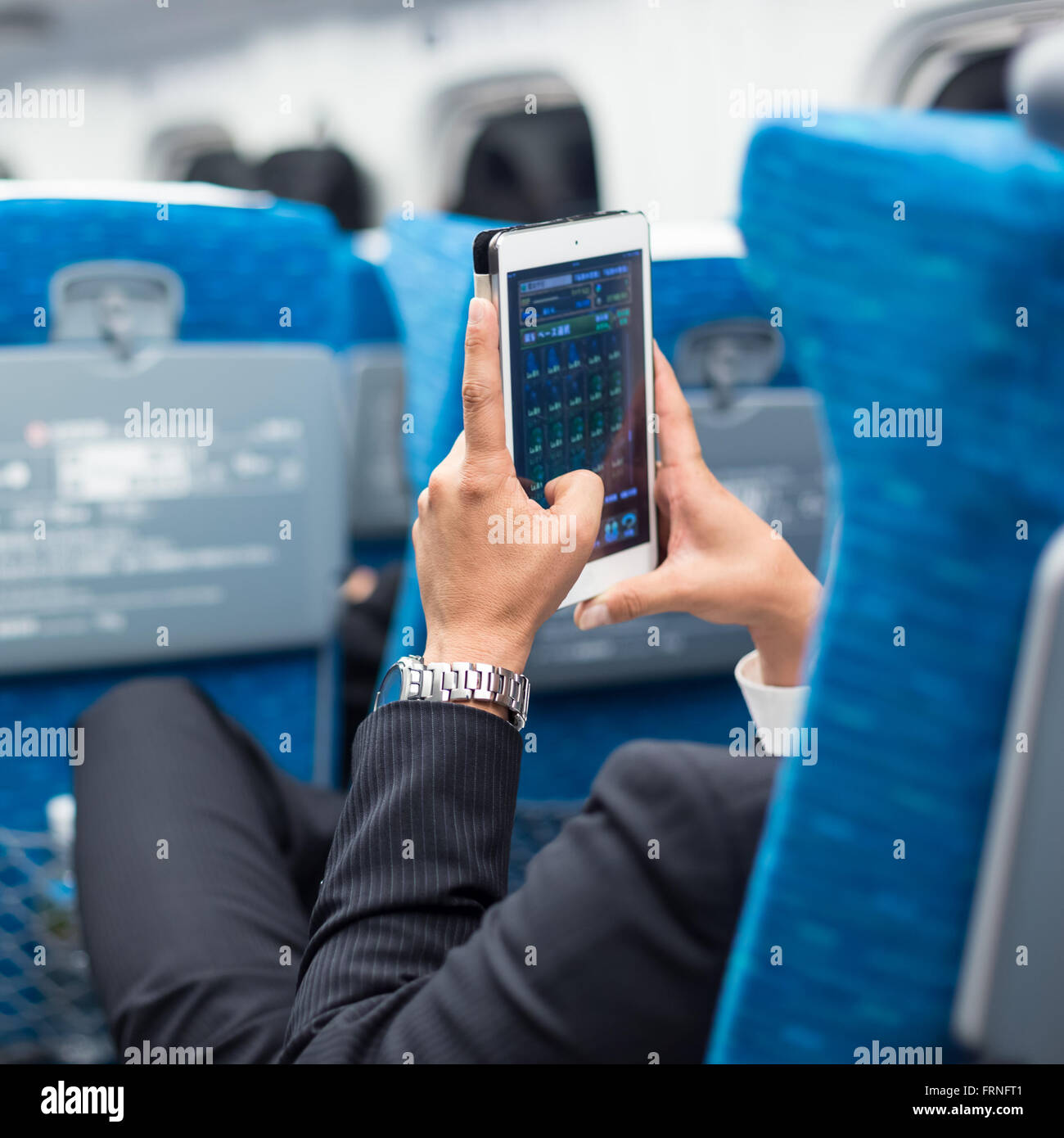 Businessman using tablet phone on airplane Stock Photo Alamy
