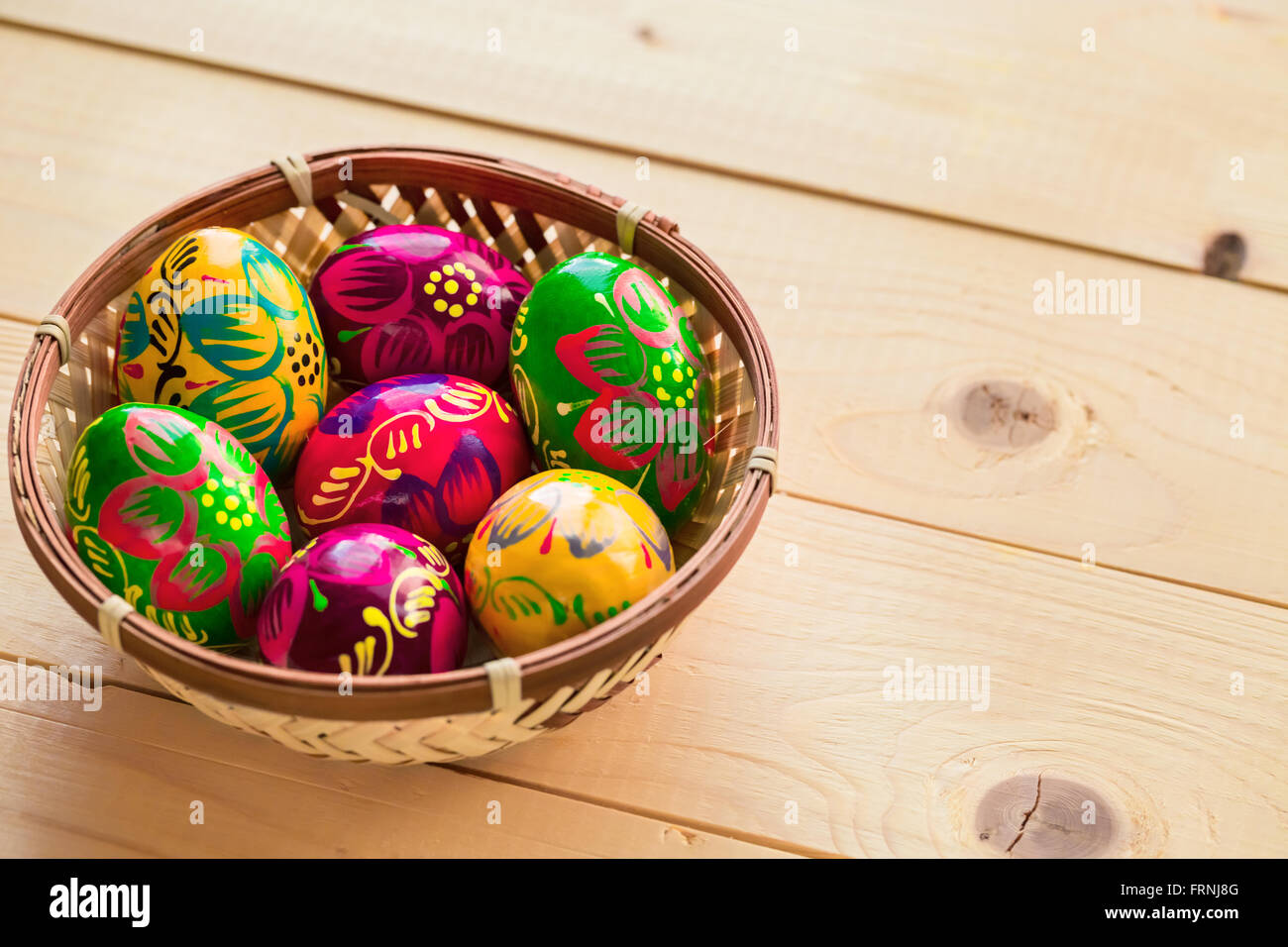 Beautiful painted colorful Easter eggs in a wickerwork nest on a light ...