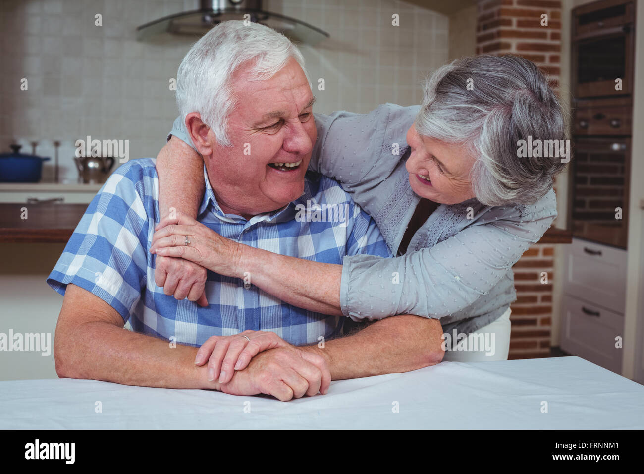 Romantic senior couple embracing in kitchen Stock Photo