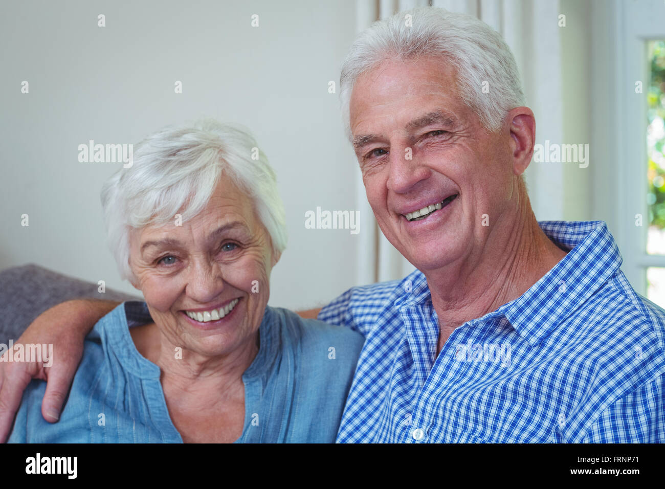 Portrait of smiling retired couple with arm around Stock Photo