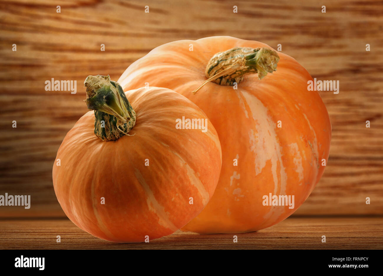 Two pumpkins on wooden shelf in closeup Stock Photo