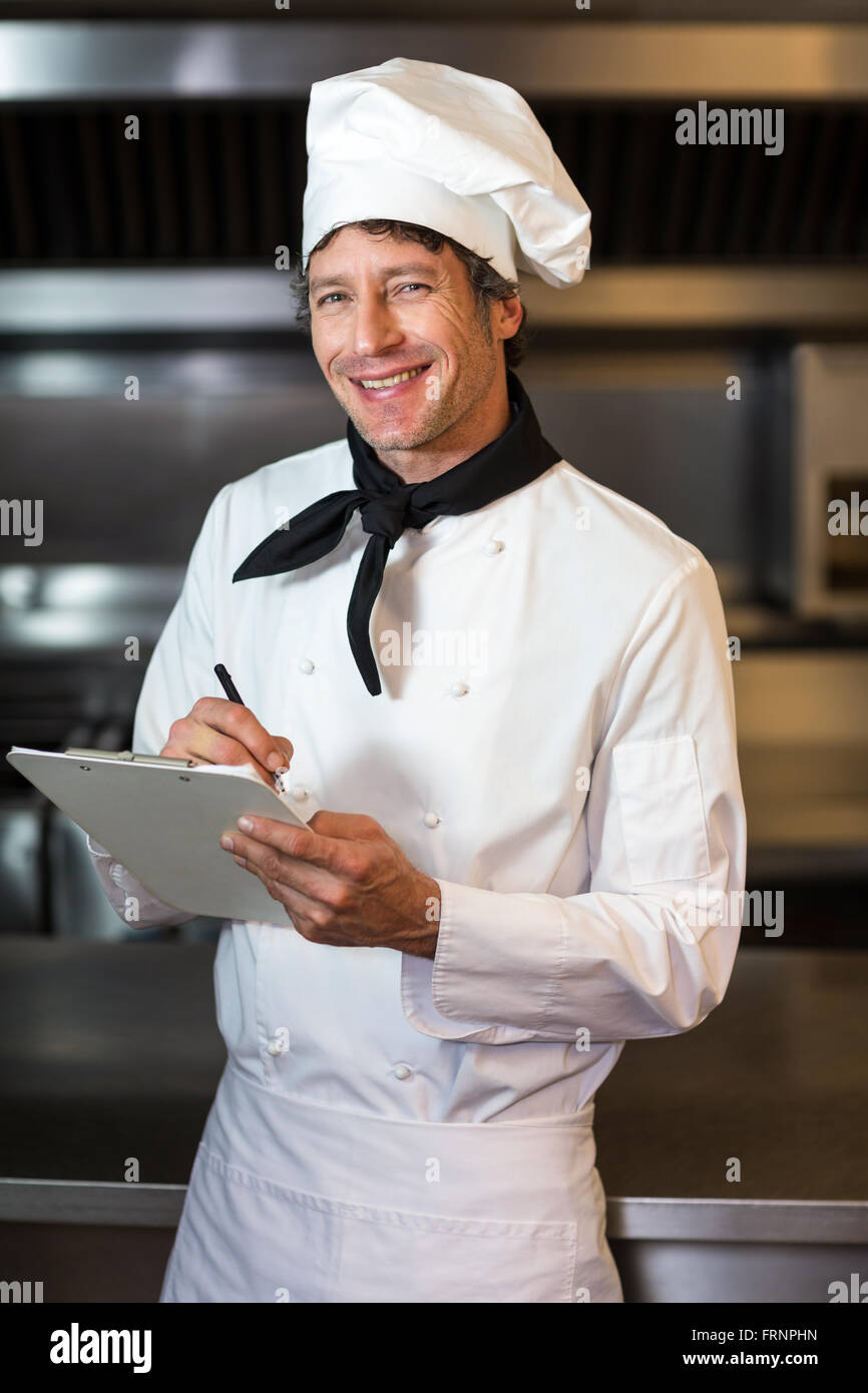 Portrait of happy chef writing on clipboard in kitchen Stock Photo Alamy