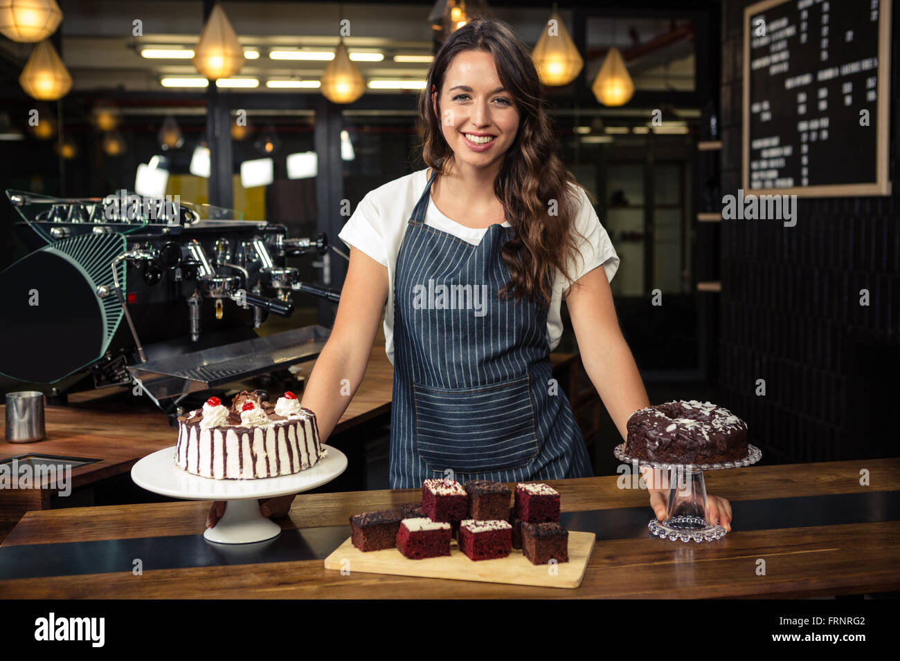 Smiling barista presenting plate with cakes Stock Photo
