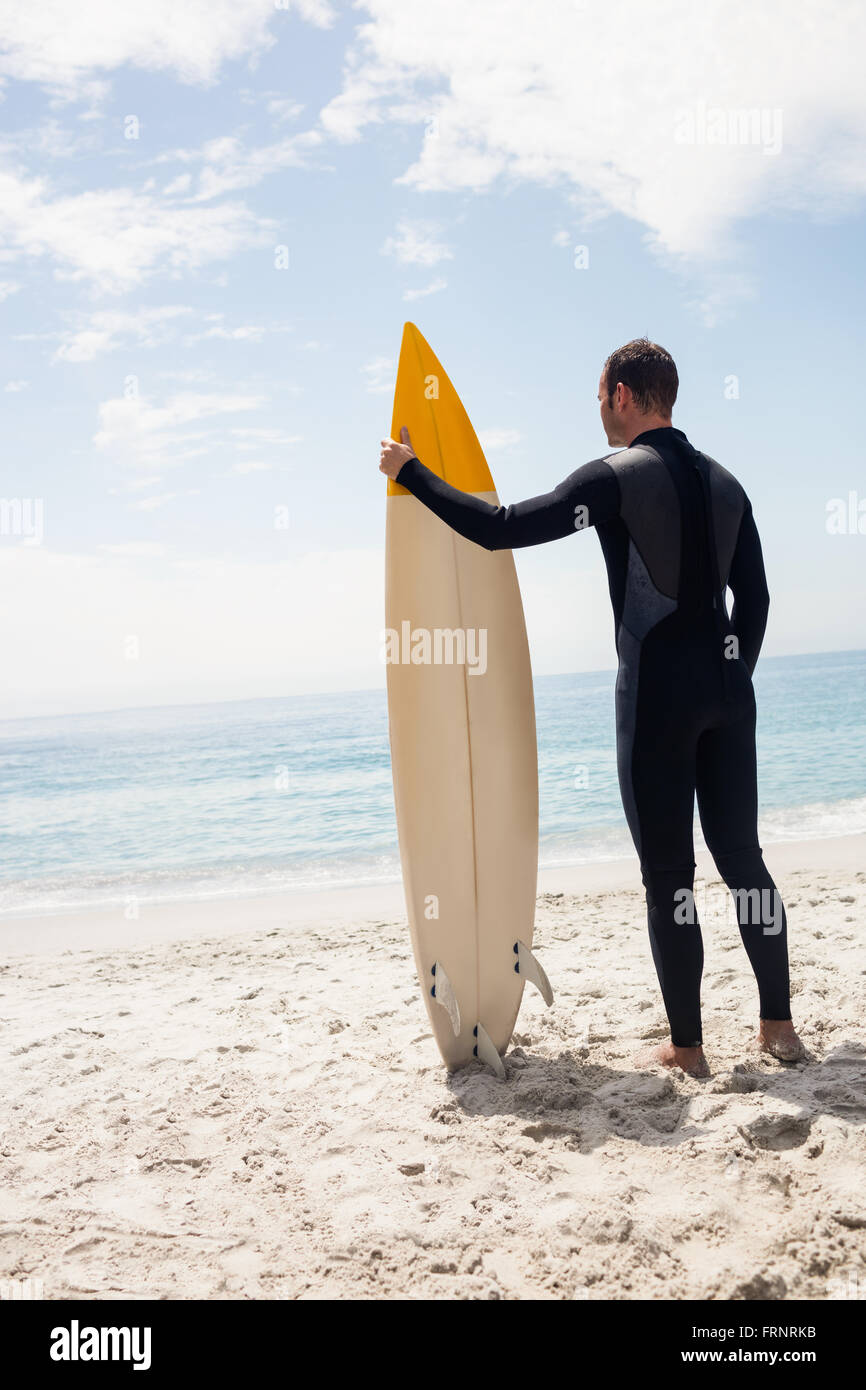 Rear view of man with surfboard standing on the beach Stock Photo - Alamy