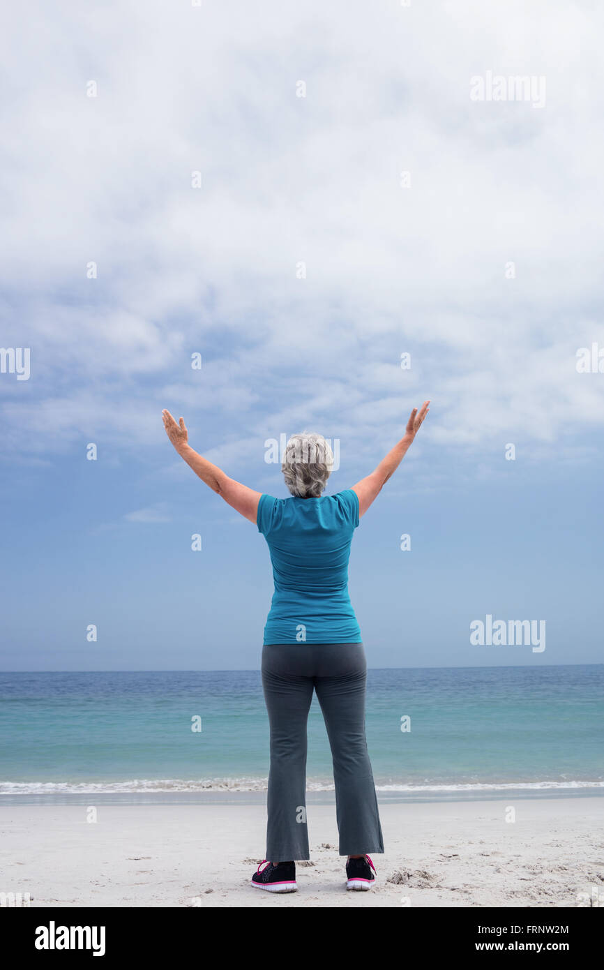 Rear view of senior woman standing on the beach Stock Photo