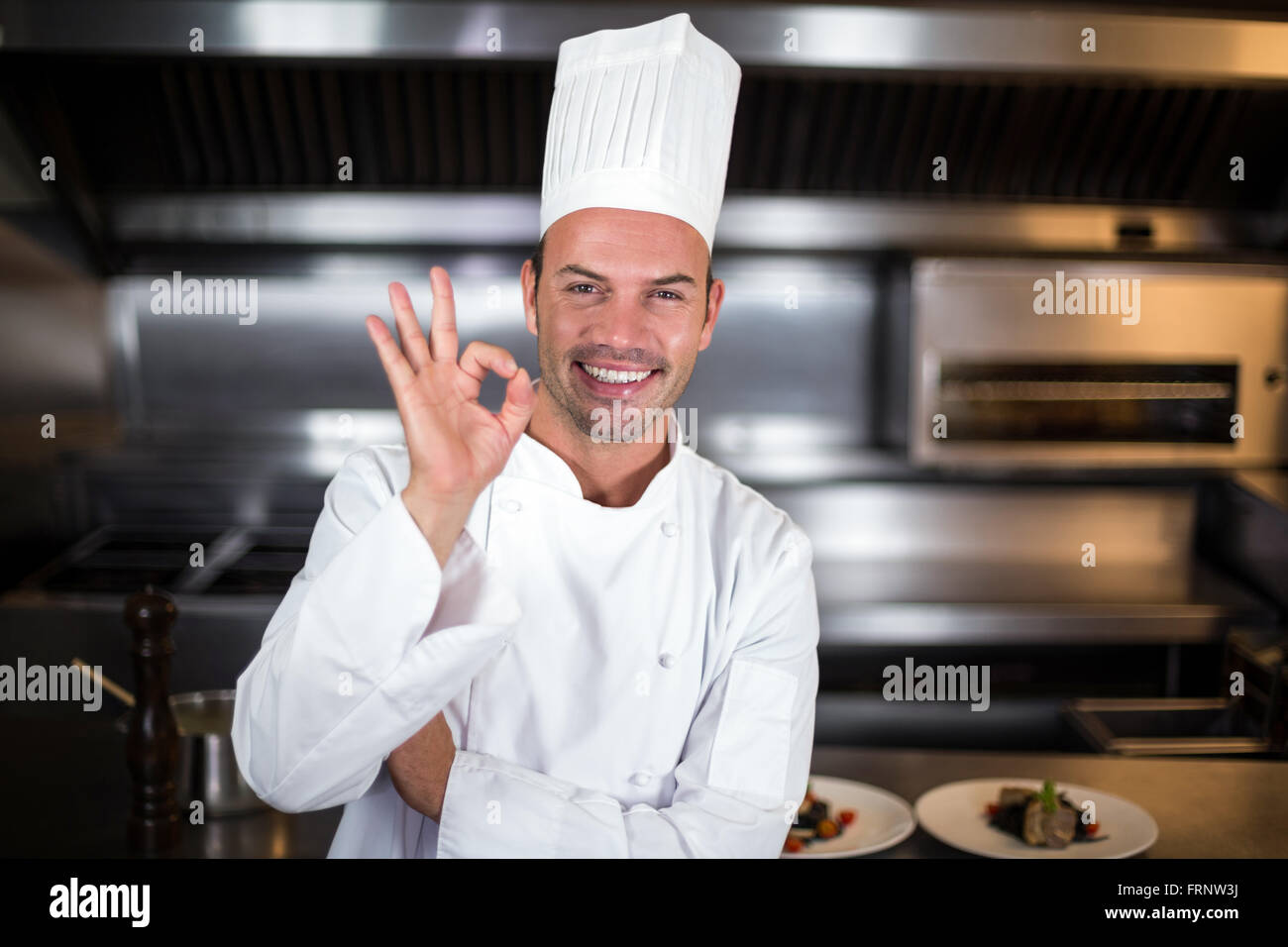 Portrait of joyful chef showing ok sign in kitchen Stock Photo