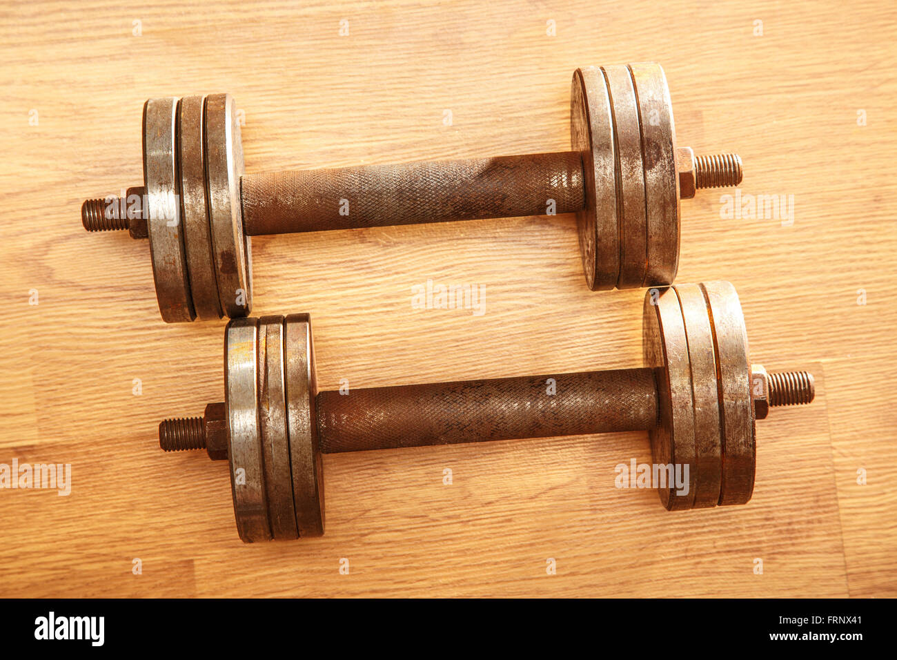 Two old metal dumbbells on wooden background Stock Photo