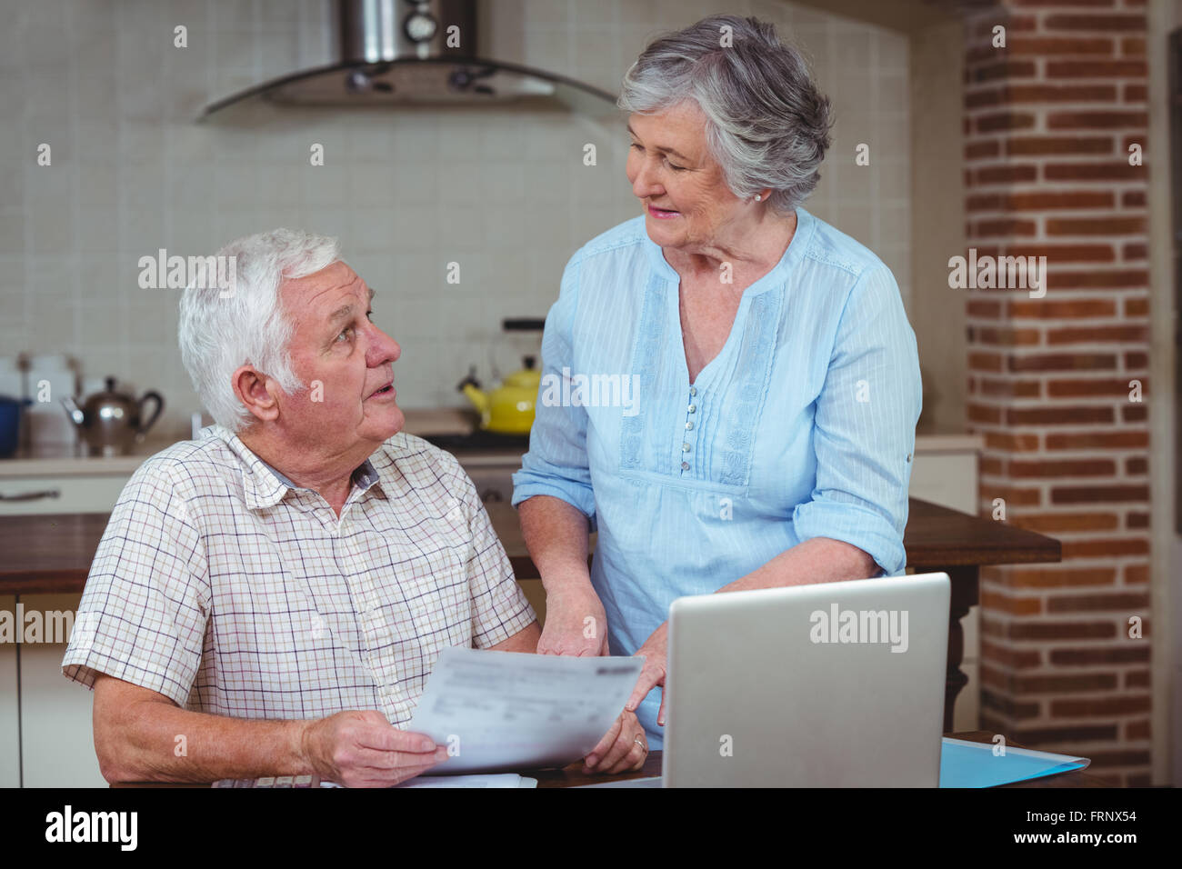 Retired couple discussing while calculating bills with laptop Stock Photo