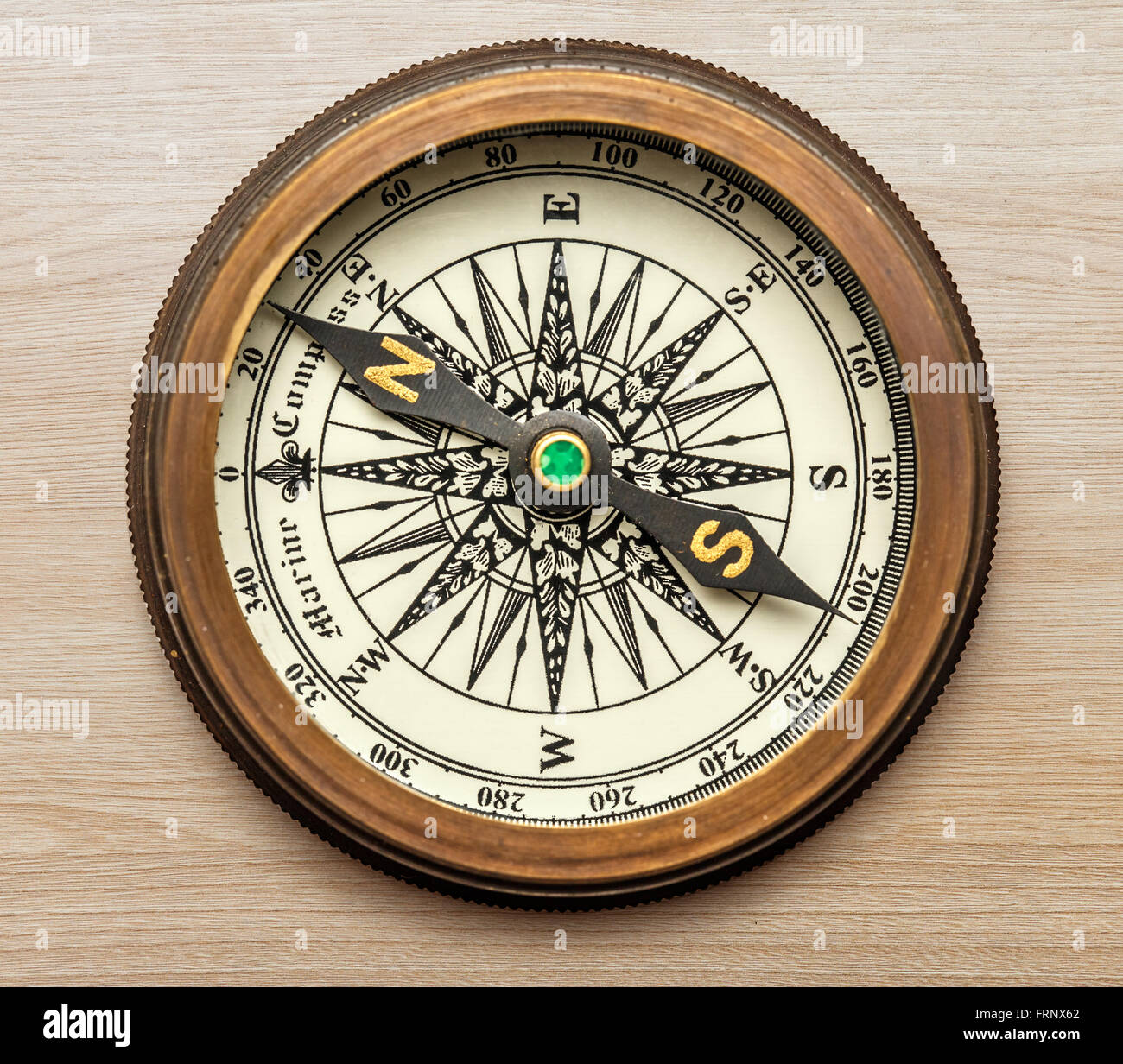 Golden vintage compass on wooden in closeup Stock Photo - Alamy