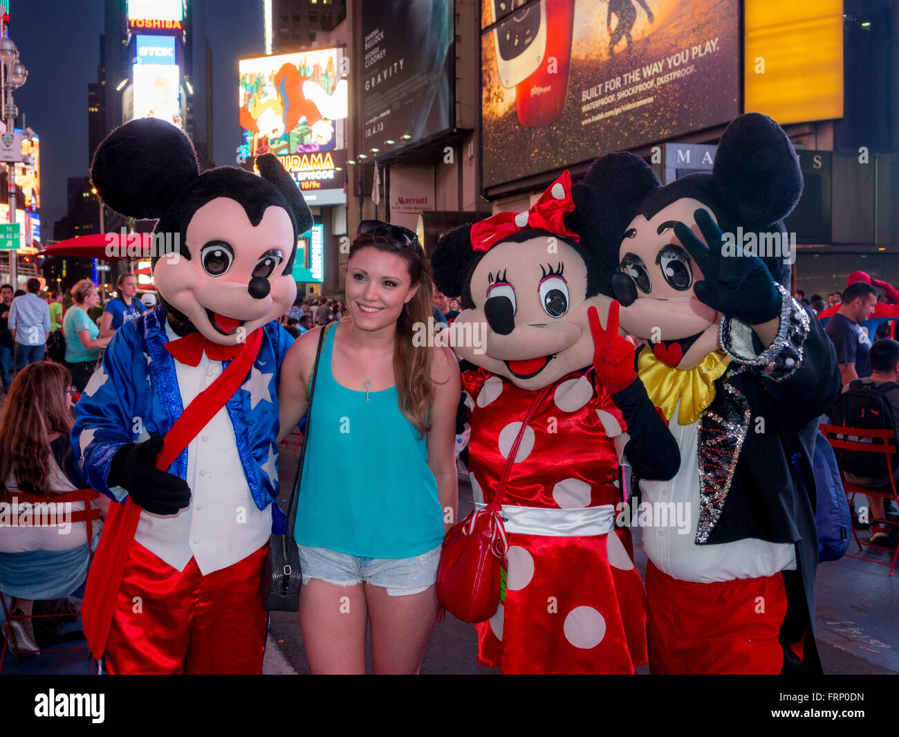 Female tourist with Mickey and Minnie Mouse characters, Times Square at night, New York City, USA. Stock Photo