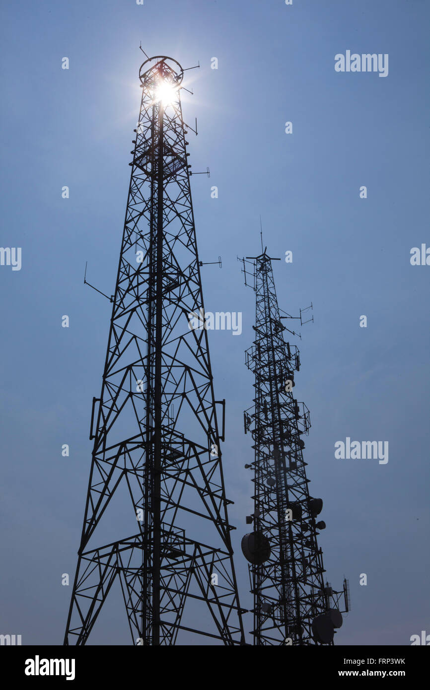 Tv, television and radio masts in silhouette against a deep blue sky adn sun. Stock Photo