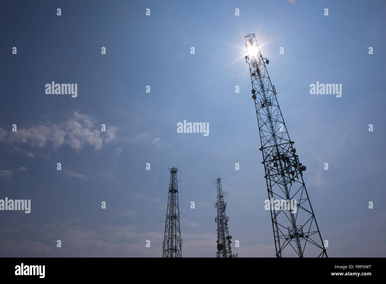 Tv, television and radio masts in silhouette against a deep blue sky adn sun. Stock Photo