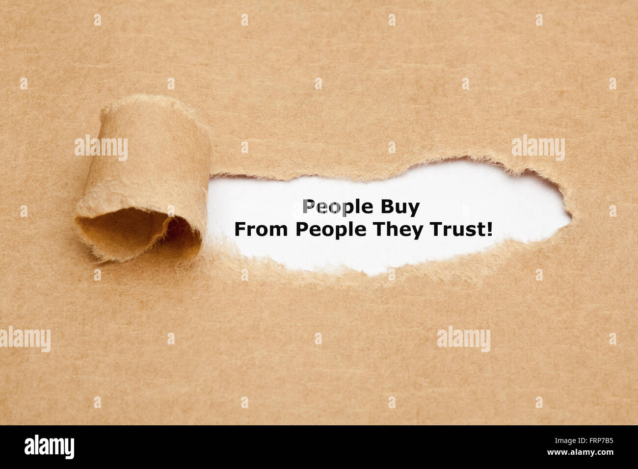 The motivational quote People Buy From People They Trust, appearing behind torn brown paper. Stock Photo