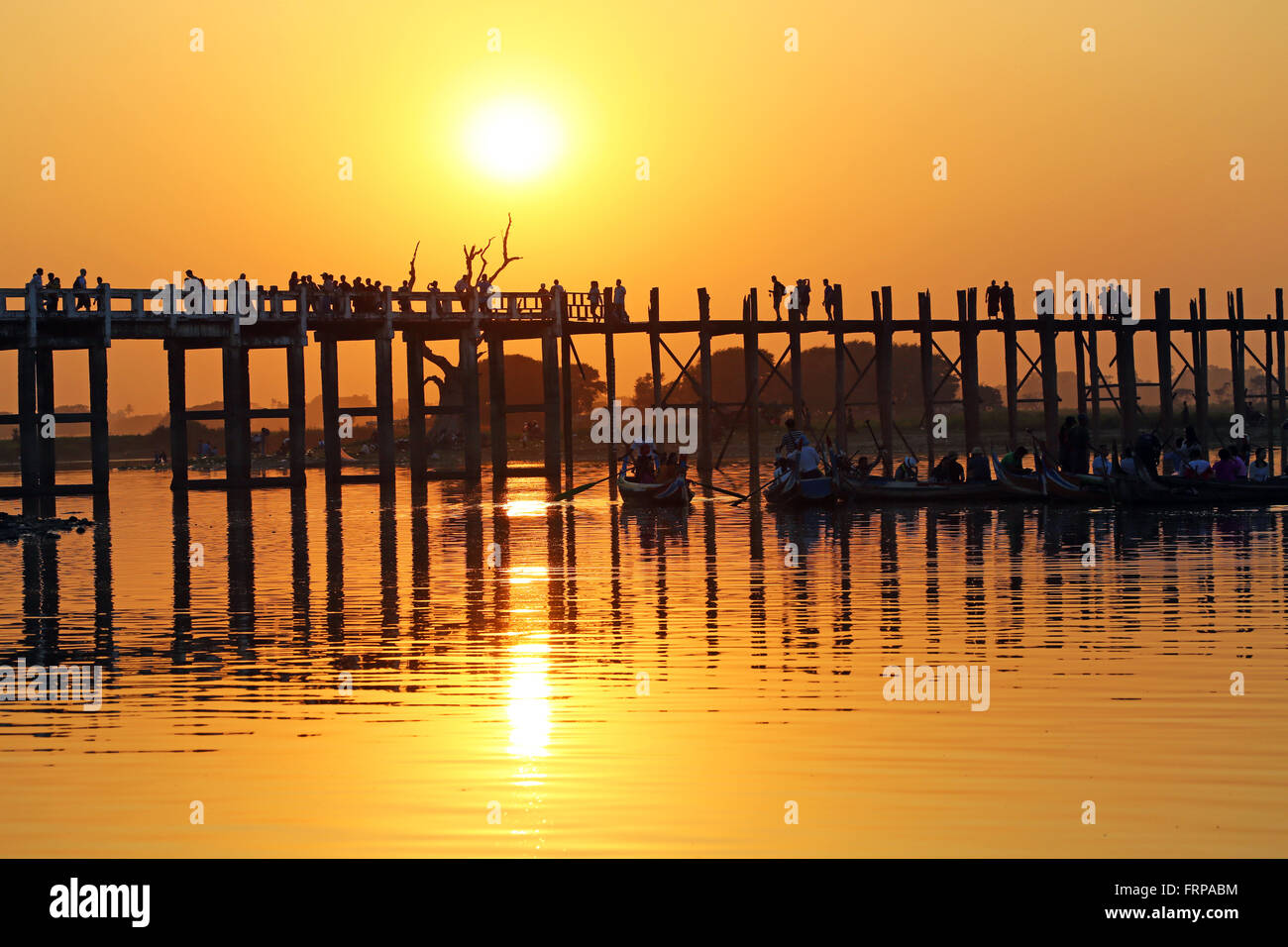 People crossing the U Bein Bridge across the Taungthaman Lake at sunset ...