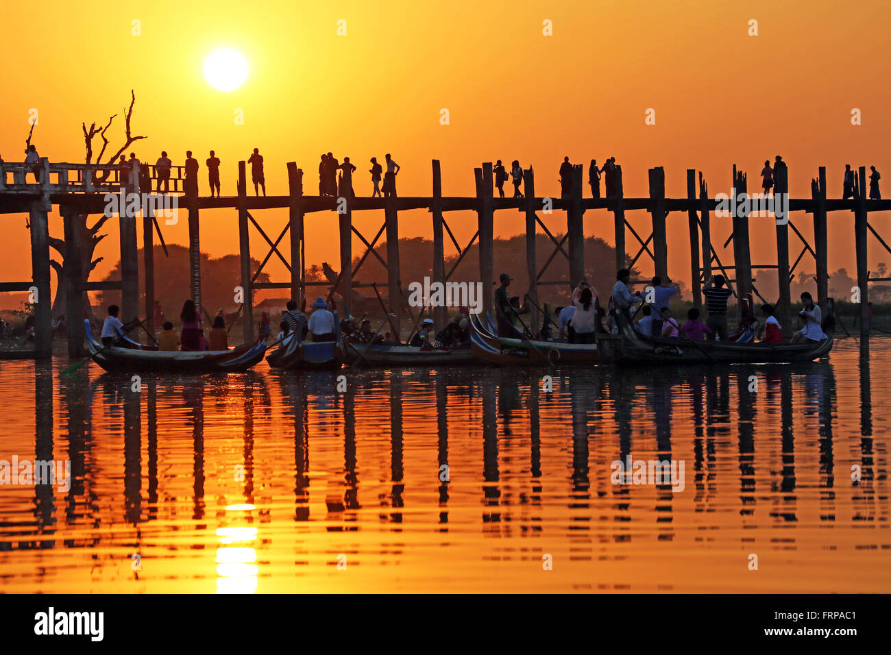 People crossing the U Bein Bridge across the Taungthaman Lake at sunset ...