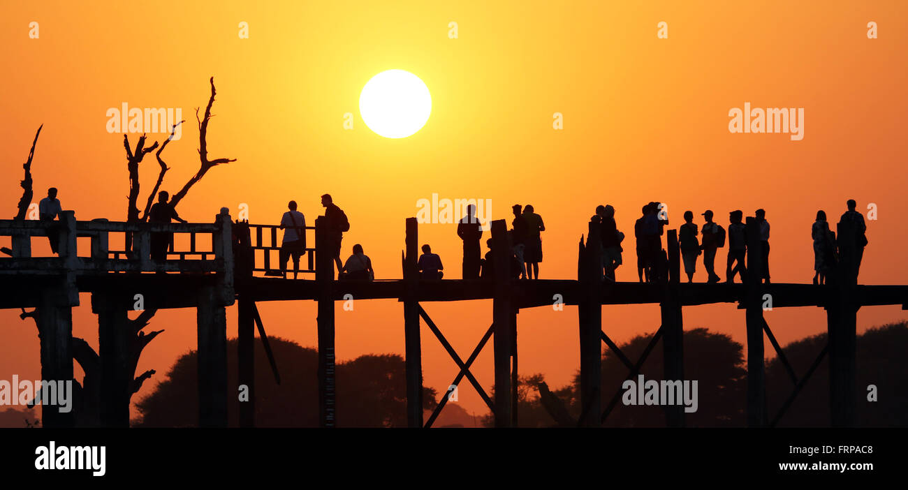 People crossing the U Bein Bridge across the Taungthaman Lake at sunset ...