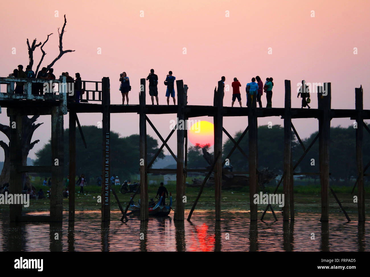 People crossing the U Bein Bridge across the Taungthaman Lake at sunset ...