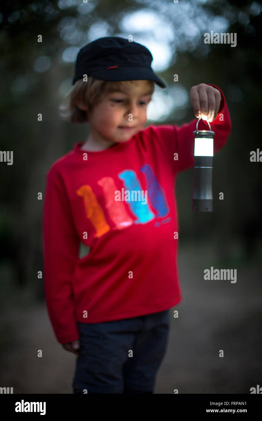 A little boy and his light, in a dark forest. Stock Photo