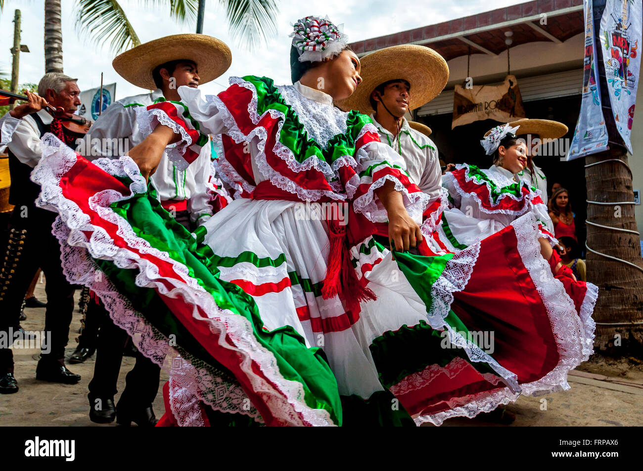 Sayulita, Nayarit: Mexican dancers wear the bright colors of Mexico's flag (red, white, green) dancing in parade with mariachis. Stock Photo