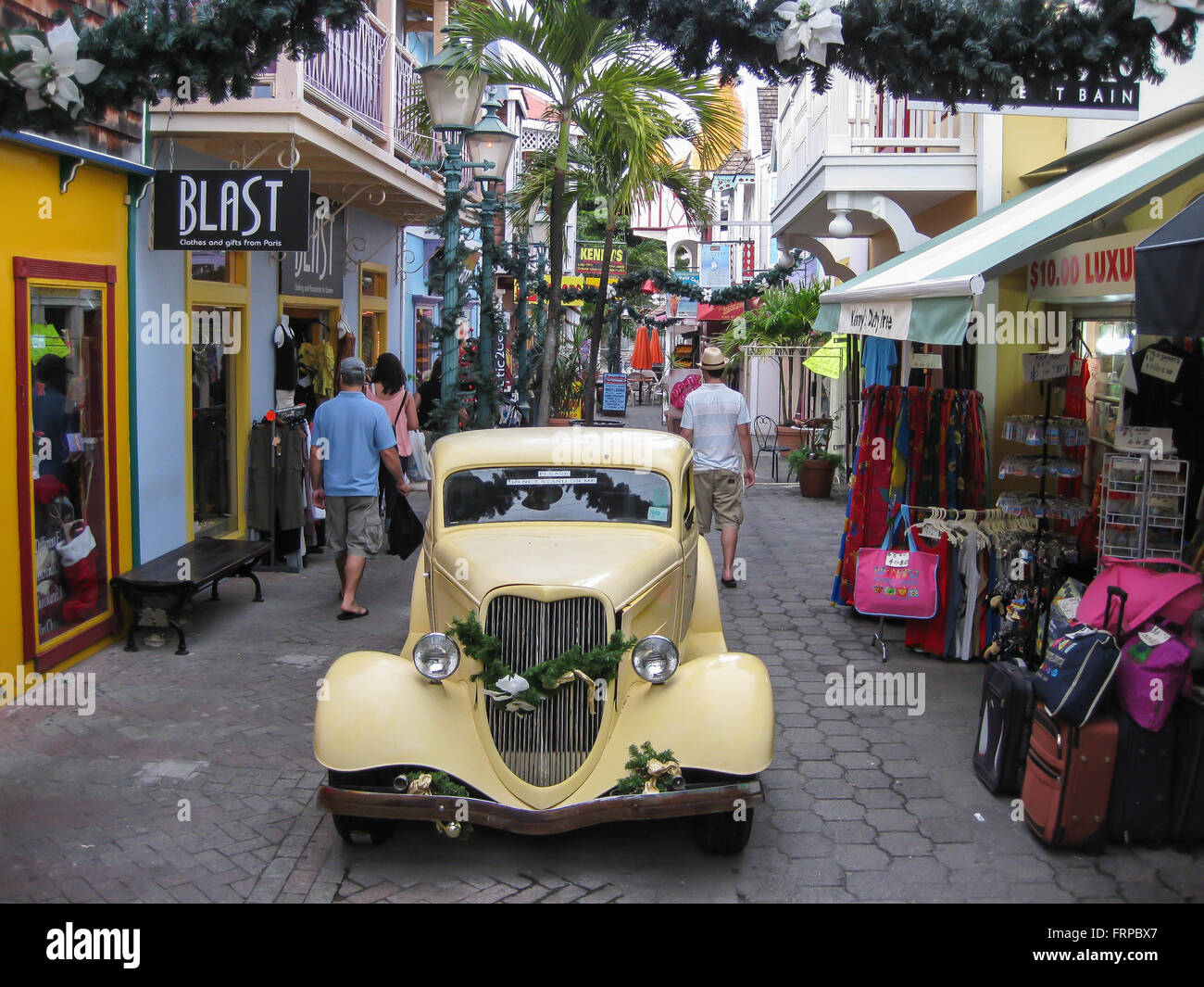 A classic automobile is parked in the center of the street in