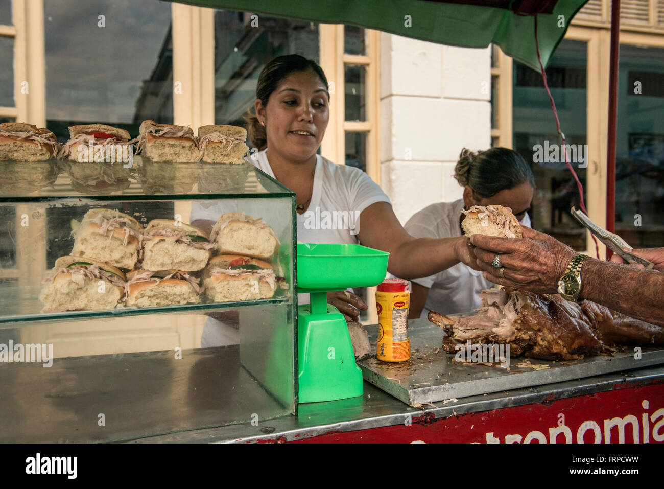 Woman Street Vendor Hands a Cuban Sandwich to a Customer, Santa Clara