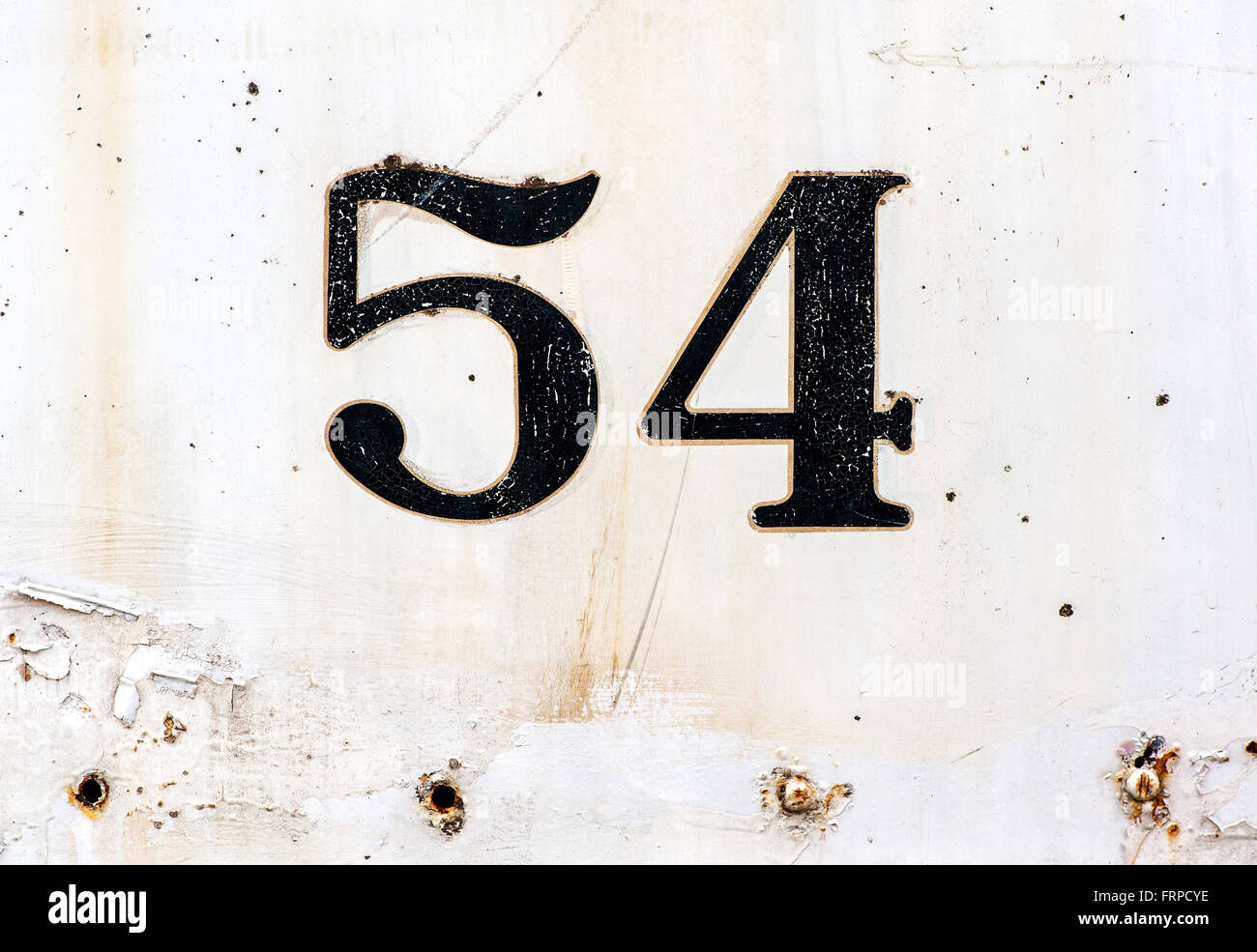 Number 54 plated on old rusty white painted surface with some missing rivets and other defects Stock Photo