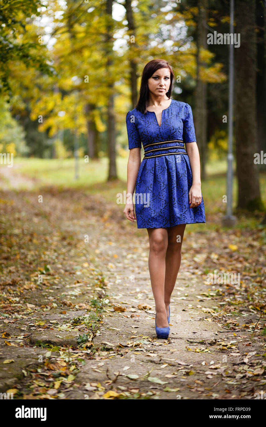 Brunette girl in blue dress walking at park. Stock Photo