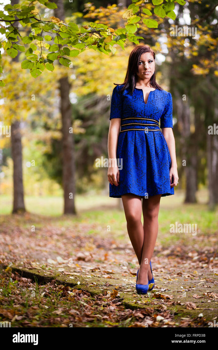 Brunette girl in blue dress walking at park. Stock Photo