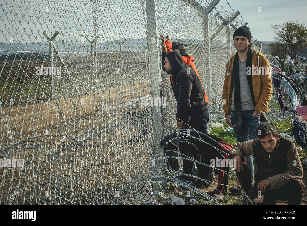 Idomeni refugee camp on the Greece Macedonia border, young men standing at the barbed wire border fence, Idomeni Stock Photo