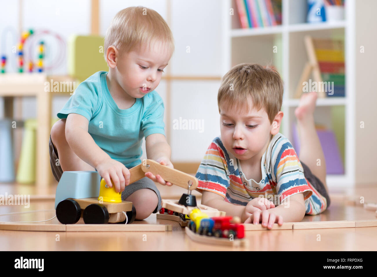 children  playing rail road and car toys in playroom Stock Photo