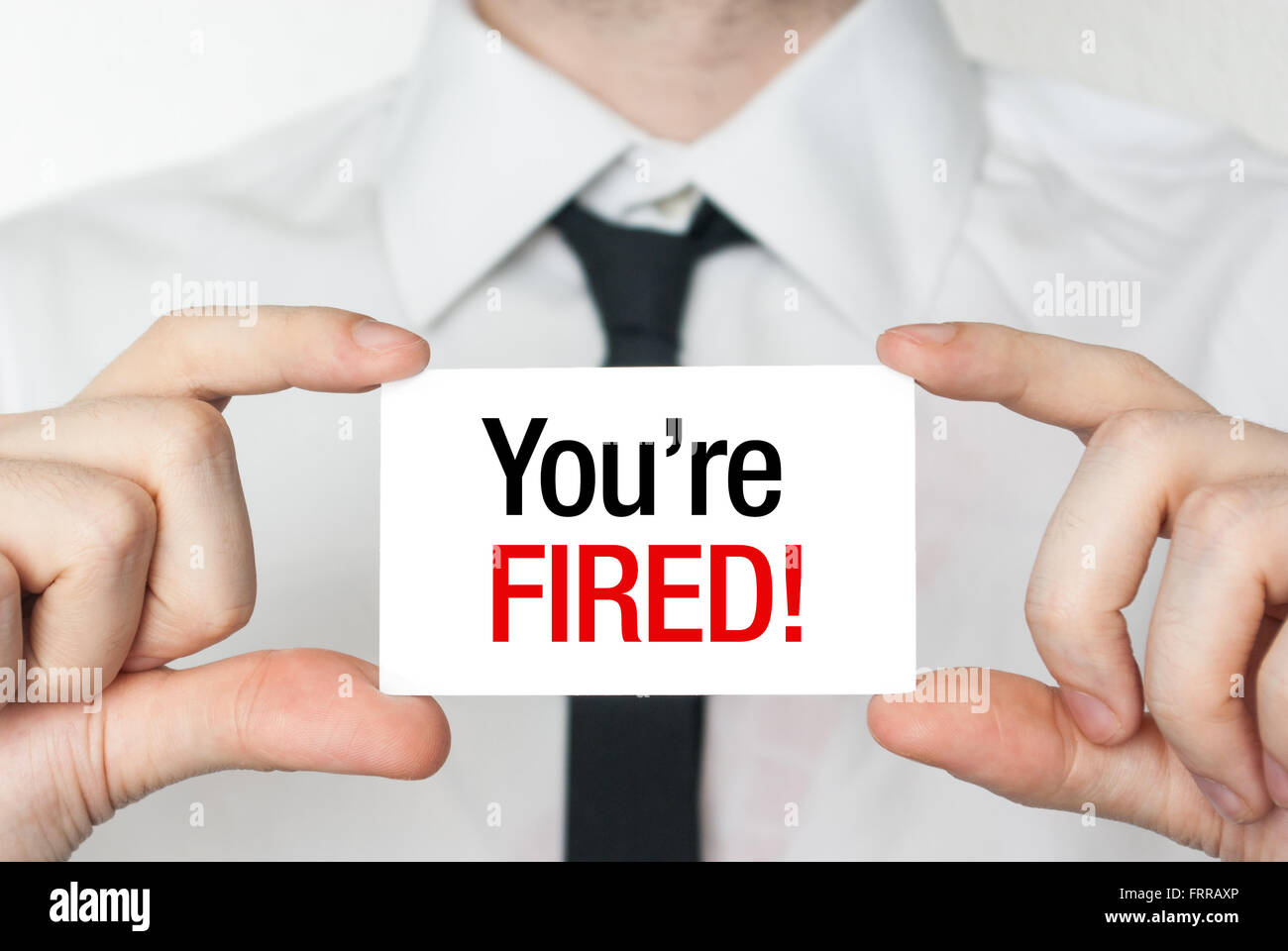 Business man holding a card with you're fired text Stock