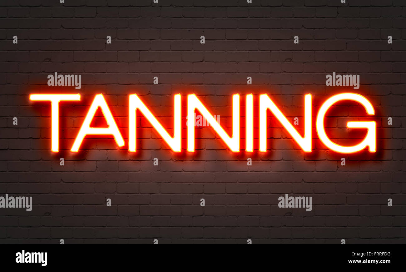 Tanning neon sign on brick wall background Stock Photo
